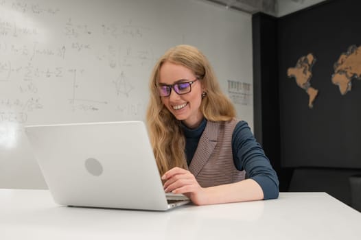 Caucasian woman scientist typing on laptop. White board with formulas