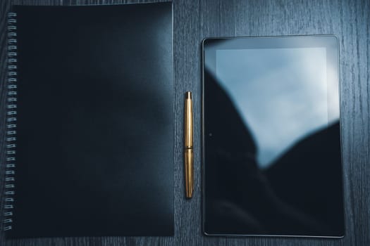 Workplace. Notebook with pen and tablet on a wooden table. Strict style. High quality photo