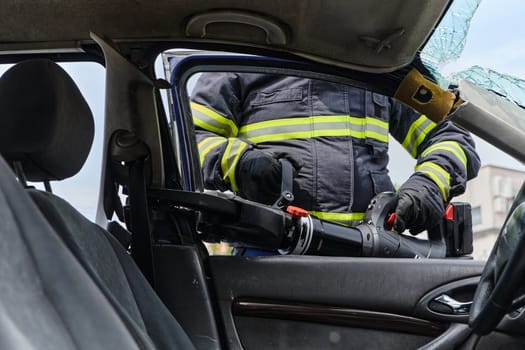 A dedicated team of professional firefighters employs specialized tools to cut and break through vehicle wreckage, showcasing their skilled collaboration and swift response in rescuing individuals involved in a car accident.