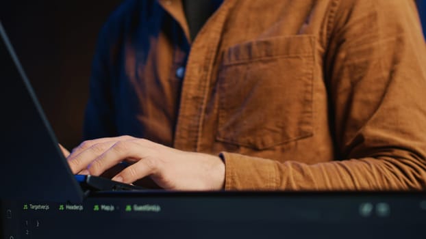 Programmer concentrating on writing complex binary code scripts on laptop terminal, close up shot. Teleworking IT specialist standing in home office, using programming to safeguard consumer data