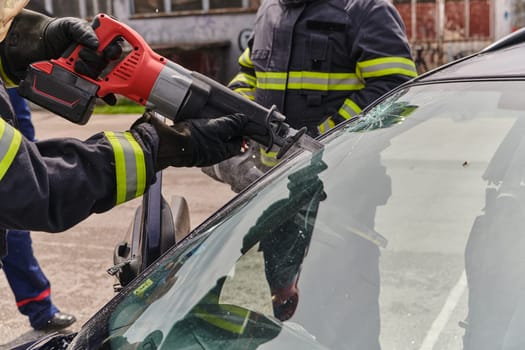 A dedicated team of professional firefighters employs specialized tools to cut and break through vehicle wreckage, showcasing their skilled collaboration and swift response in rescuing individuals involved in a car accident.