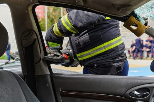 A dedicated team of professional firefighters employs specialized tools to cut and break through vehicle wreckage, showcasing their skilled collaboration and swift response in rescuing individuals involved in a car accident.