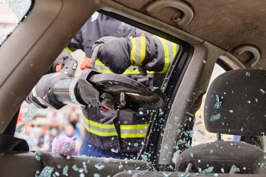 A dedicated team of professional firefighters employs specialized tools to cut and break through vehicle wreckage, showcasing their skilled collaboration and swift response in rescuing individuals involved in a car accident.