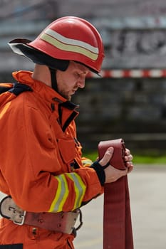 A dedicated firefighter meticulously coils the fire hose after successfully extinguishing a blaze, showcasing the critical post-incident responsibilities.