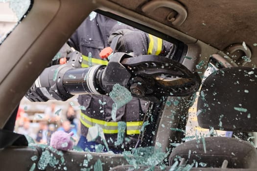 A dedicated team of professional firefighters employs specialized tools to cut and break through vehicle wreckage, showcasing their skilled collaboration and swift response in rescuing individuals involved in a car accident.