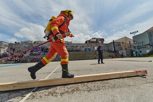 In a dynamic display of synchronized teamwork, firefighters hustle to carry, connect, and deploy firefighting hoses with precision, showcasing their intensive training and readiness for challenging and high-risk situations ahead.