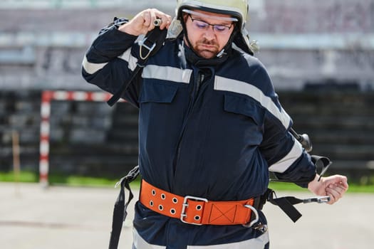 A firefighter dons the essential components of their professional gear, embodying resilience, commitment, and readiness as they gear up for a hazardous firefighting mission, a testament to their unwavering dedication to protecting and saving lives.