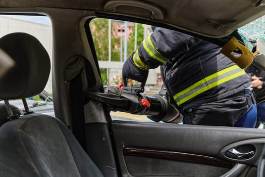 A dedicated team of professional firefighters employs specialized tools to cut and break through vehicle wreckage, showcasing their skilled collaboration and swift response in rescuing individuals involved in a car accident.