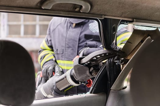 A dedicated team of professional firefighters employs specialized tools to cut and break through vehicle wreckage, showcasing their skilled collaboration and swift response in rescuing individuals involved in a car accident.