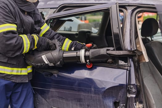 A dedicated team of professional firefighters employs specialized tools to cut and break through vehicle wreckage, showcasing their skilled collaboration and swift response in rescuing individuals involved in a car accident.