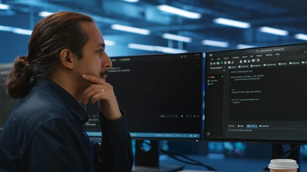 Computer scientist in server hub doing system analysis, coding, doing needed adjustments for supercomputers to run. Expert working in data center housing advanced storage infrastructure