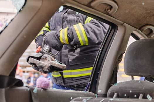 A dedicated team of professional firefighters employs specialized tools to cut and break through vehicle wreckage, showcasing their skilled collaboration and swift response in rescuing individuals involved in a car accident.