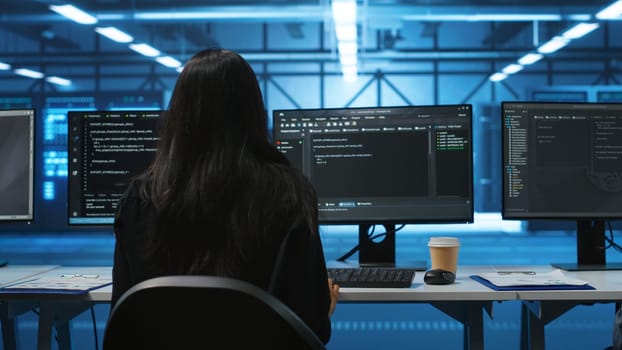 IT support employee in data center putting headphones on to talk with coworkers, coding on computer. Woman in remote call meeting with colleagues using headset microphone, overseeing server clusters