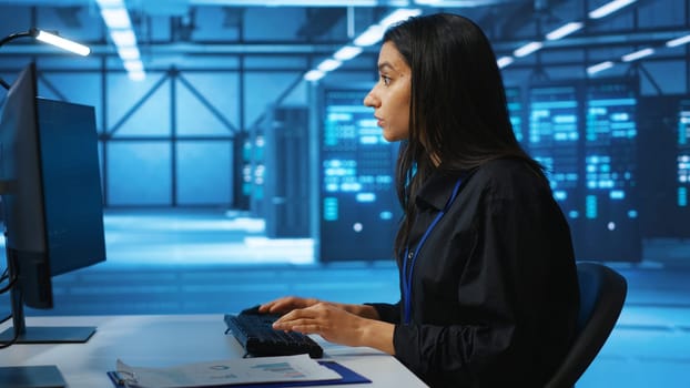 IT engineer looking at PC screen, working in network security data center, ensuring optimal performance. Woman monitoring energy consumption across operational server rigs components, close up shot