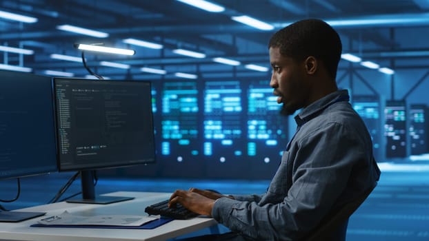 Software developer programming in high tech facility with server rows providing computing resources for different workloads. IT expert supervising data center supercomputers