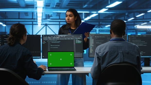 Isolated screen laptop in front of IT support workers coding on computers and talking with managers, upgrading equipment. Engineers at PC desk overseeing server clusters using chroma key notebook