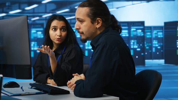 IT technicians in server farm brainstorming ways to repair equipment storing datasets. Colleagues at work in data center discussing how to mend rigs doing computational operations