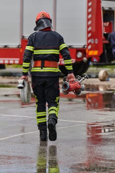 In a dynamic display of synchronized teamwork, firefighters hustle to carry, connect, and deploy firefighting hoses with precision, showcasing their intensive training and readiness for challenging and high-risk situations ahead.