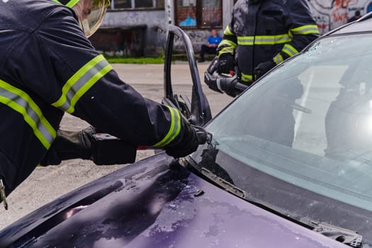 A dedicated team of professional firefighters employs specialized tools to cut and break through vehicle wreckage, showcasing their skilled collaboration and swift response in rescuing individuals involved in a car accident.