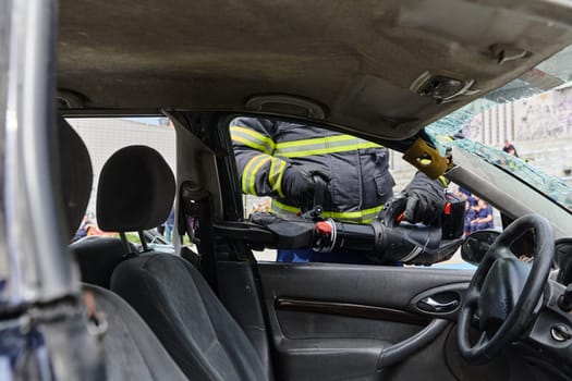 A dedicated team of professional firefighters employs specialized tools to cut and break through vehicle wreckage, showcasing their skilled collaboration and swift response in rescuing individuals involved in a car accident.