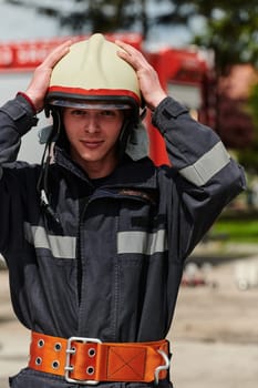 A firefighter, adorned in professional gear, stands confidently beside a fire truck following a grueling firefighting training session