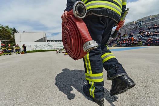 In a dynamic display of synchronized teamwork, firefighters hustle to carry, connect, and deploy firefighting hoses with precision, showcasing their intensive training and readiness for challenging and high-risk situations ahead.