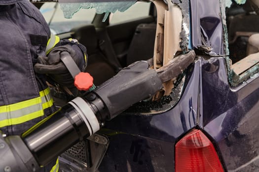 A dedicated team of professional firefighters employs specialized tools to cut and break through vehicle wreckage, showcasing their skilled collaboration and swift response in rescuing individuals involved in a car accident.