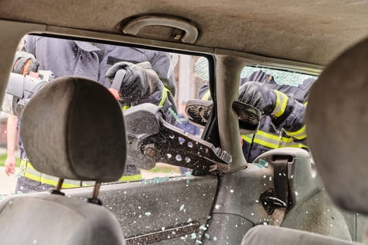 A dedicated team of professional firefighters employs specialized tools to cut and break through vehicle wreckage, showcasing their skilled collaboration and swift response in rescuing individuals involved in a car accident.