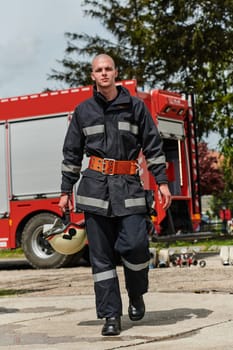 A firefighter, adorned in professional gear, stands confidently beside a fire truck following a grueling firefighting training session