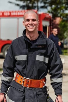 A firefighter, adorned in professional gear, stands confidently beside a fire truck following a grueling firefighting training session