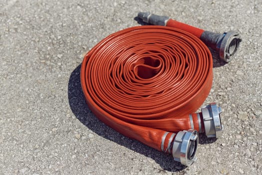 A neatly coiled fire hose lies on the ground, prepared and ready for immediate use in firefighting operations