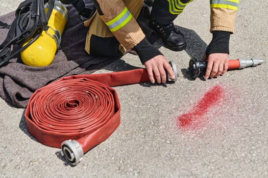 A dedicated firefighter meticulously coils the fire hose after successfully extinguishing a blaze, showcasing the critical post-incident responsibilities.