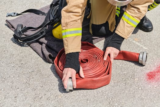 A dedicated firefighter meticulously coils the fire hose after successfully extinguishing a blaze, showcasing the critical post-incident responsibilities.