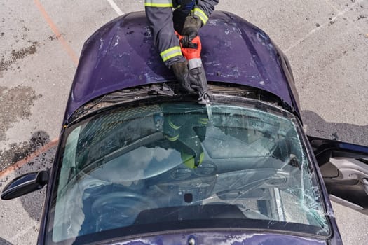 A dedicated team of professional firefighters employs specialized tools to cut and break through vehicle wreckage, showcasing their skilled collaboration and swift response in rescuing individuals involved in a car accident.