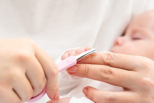 The photo emphasizes the profound care as a mother delicately trims her newborn baby's nails with