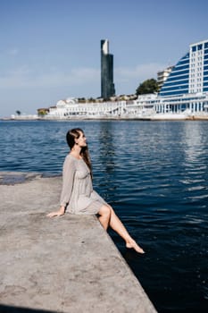 A woman is sitting in the water wearing a white dress. The water is calm and blue. The woman is enjoying the moment and taking in the beauty of the scene