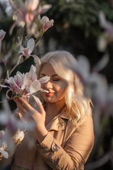 Magnolia flowers woman. A woman is holding a magnolia flower in her hand and standing in front of a tree. Concept of serenity and beauty, as the woman is surrounded by nature and the flower adds a touch of color