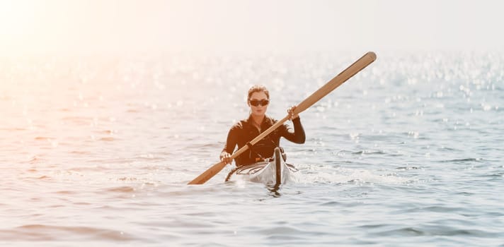 Happy smiling woman in kayak on ocean, paddling with wooden oar. Calm sea water and horizon in background