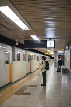 Woman waiting for subway train in station. Concept of travel and urban commuting.