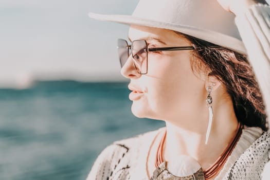 Portrait of a curly haired woman in a white hat and glasses on the background of the sea