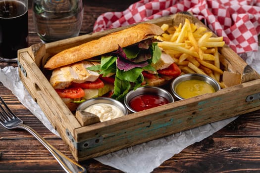 Grilled chicken breast sandwich with french fries and sauces
