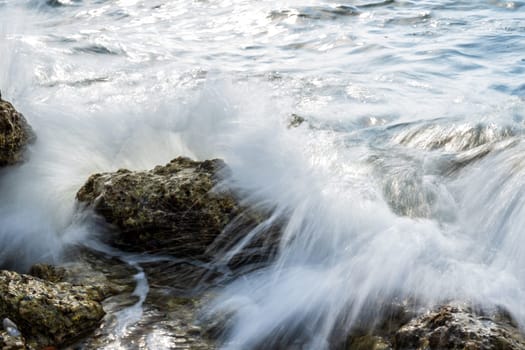 Sea waves hitting rocks on the coastline on a sunny day