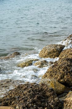 Sea waves hitting rocks on the coastline on a sunny day