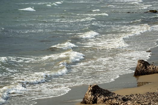 View from below of sandy beach and waves at sunset