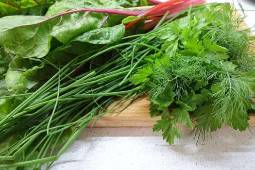 Fresh herbs on wooden board. Dill, green onion, parsley, churd.