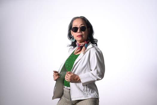 Fashionable middle age woman in sunglasses posing isolated over white background.