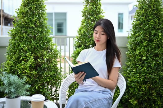 Young Asian woman in casual clothes reading book in the garden.