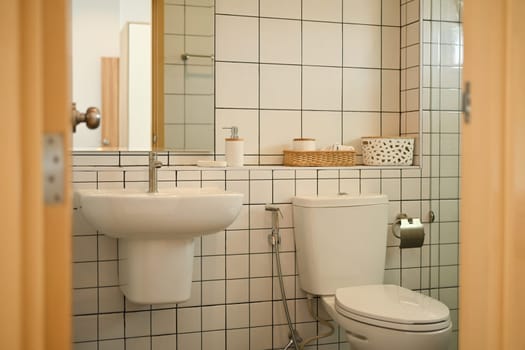 Bathroom interior with ceramic toilet bowl and wash basin, minimal decoration.