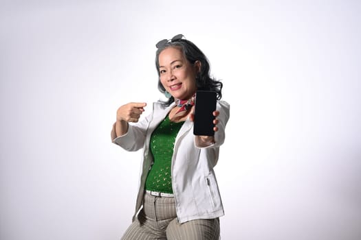 Confident middle age woman showing mobile phone isolated on white background.