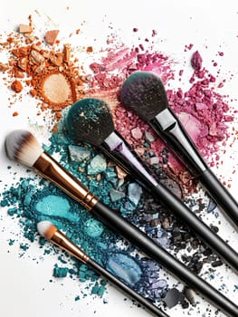 Four makeup brushes arranged on a white background with crushed eyeshadow and blush.
